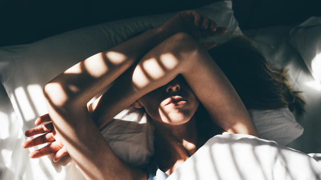 Sad and depressed woman lying in bed at home. 