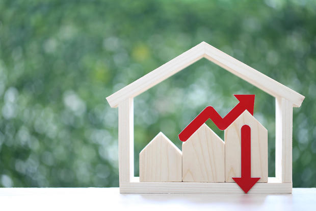 Model house and red arrow graph on natural green background, business investment and real estate concept 