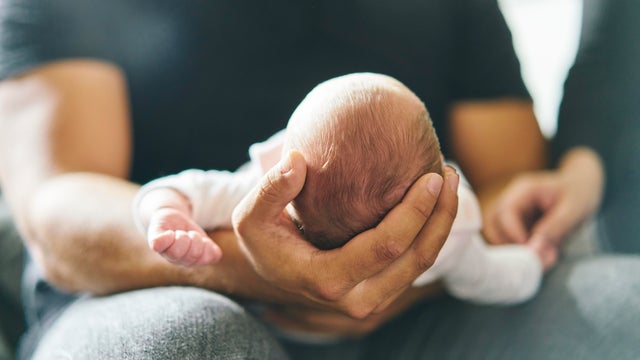 Father supporting head of baby on lap 