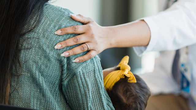 Unrecognizable person touches a mother's shoulder 