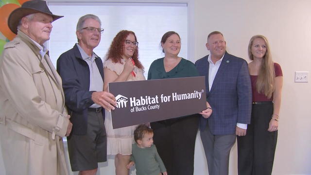 Mariela poses for a photo with other people and a Habitat for Humanity sign 