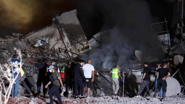 People inspect damage at the site of an Israeli strike in Beirut 