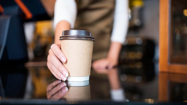 Please enjoy drinking a coffee. The unrecognizable waitress serving coffee to a customer in a cafe. Serving food and Drink, Point of Sale System.