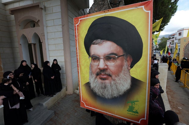 People stand near a picture of Hezbollah leader Sayyed Hassan Nasrallah