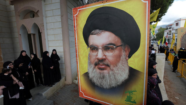 People stand near a picture of Hezbollah leader Sayyed Hassan Nasrallah 