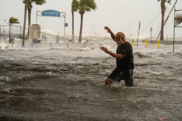 A man crosses a storm surge flooded area on the coast of Gulfport, Florida, as Hurricane Helene passed through the Gulf of Mexico to the west on Sept. 26, 2024.