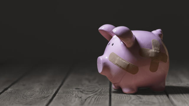 Broken piggy bank with band aid bandage or plaster finance background 