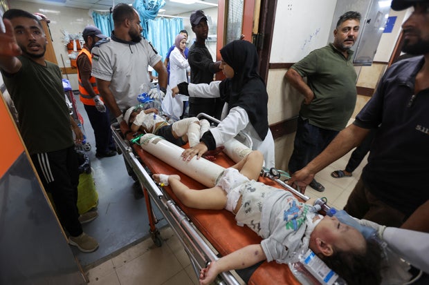 Injured children are carried on a stretcher at Al-Aqsa Martyrs Hospital, in Deir Al-Balah, in the central Gaza Strip