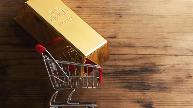 Large shiny gold bar put in a tiny shopping cart. 