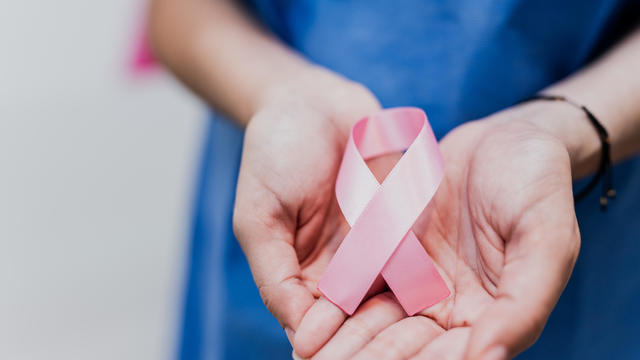 Close-up of a woman patient holding breast cancer ribbon at hospital 