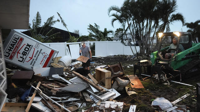 Homeowner Robert Turick, 68, left, and storm waste removal contractor Sven Barnes work to clear debris that storm surge from Hurricane Milton swept from other properties into Turick's canal-facing backyard, in Englewood, Florida, Oct. 11, 2024. 