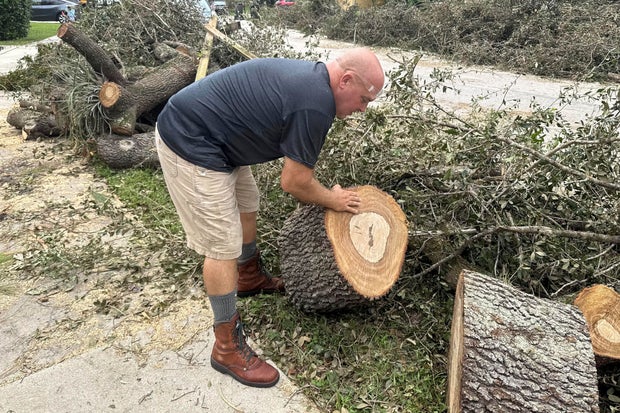 Tony Brazzale removes part of a tree felled by a tornado from in front of his house in Wellington, Florida, Oct. 11, 2024.
