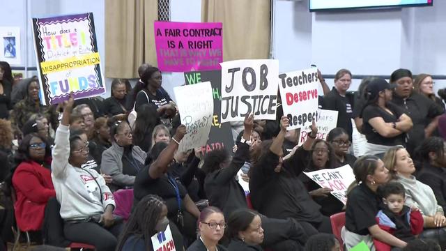 Protesters hold signs inside an East Orange Board of Education meeting. 