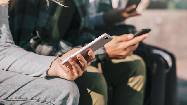 Detail of teenagers watching with their mobile phones 