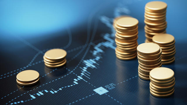 Coin Stacks Sitting on A Blue Financial Graph Background 