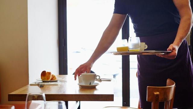 Waiter clearing table in restaurant 