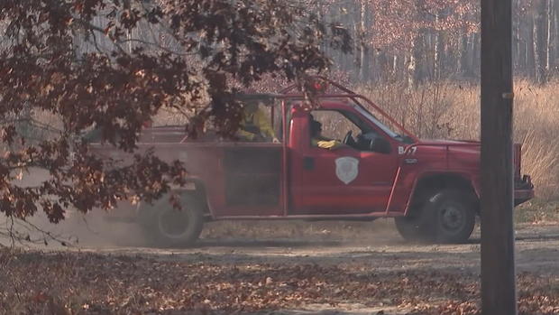 A firetruck is seen in smoky conditions near a forest 