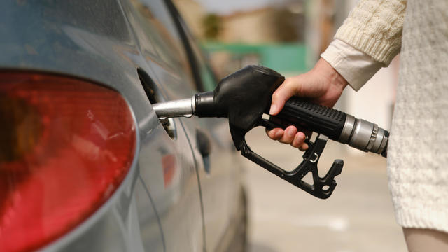 unrecognizable woman using gas pump to add fuel to her car during energy crisis 