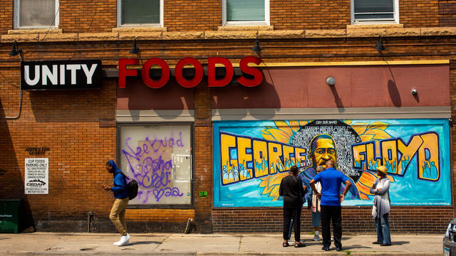 Visitors talk near the mural outside of Unity Foods, formerly C 