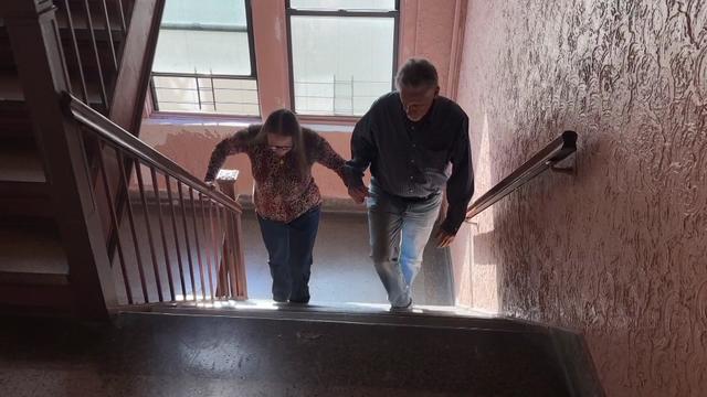 A couple climbs a stairwell inside their apartment building. 