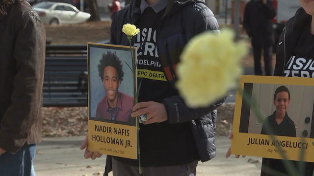 People are seen walking holding yellow carnations and posters with the names of loved ones who died in traffic incidents 