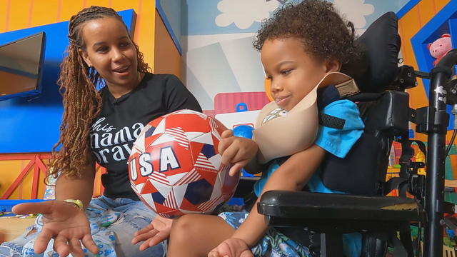 Stacey-Ann Sutherland and her son King, who is in a wheelchair, talk to a reporter in a playroom 