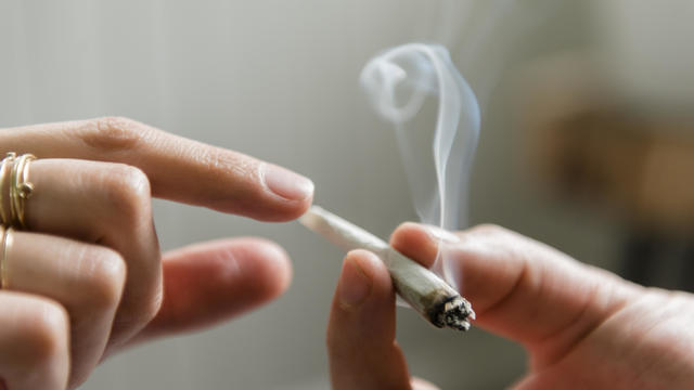 Hands of man and woman passing marijuana joint 