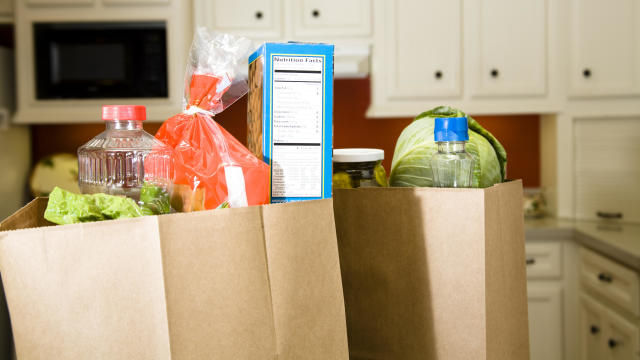 Food in grocery bags on kitchen counter. 