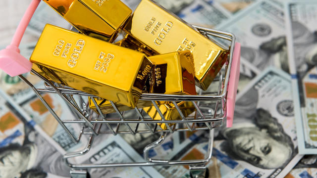 gold bars lie in a shopping cart, background with dollars. concept of money, wealth and abundance. 