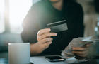 Cropped shot of young Asian woman holding credit card and expense receipts, handing personal banking and finance at home. Planning budget, calculating expenses and managing financial bills. Home budgeting. Home finances. Digital banking habits 