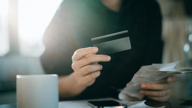 Cropped shot of young Asian woman holding credit card and expense receipts, handing personal banking and finance at home. Planning budget, calculating expenses and managing financial bills. Home budgeting. Home finances. Digital banking habits 