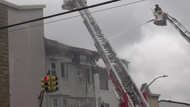 Firefighters in a bucket on a crane spray the damaged roof of a building with a hose. 