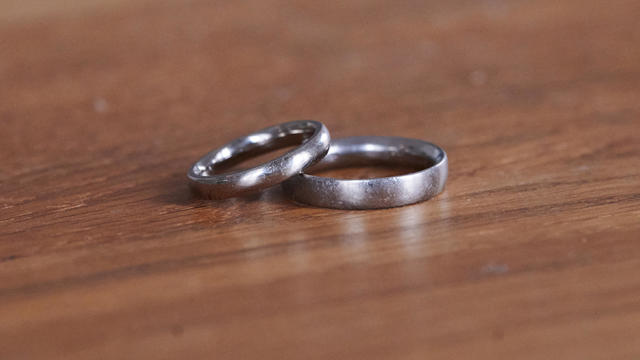 A pair of wedding rings lie on a wooden table. 