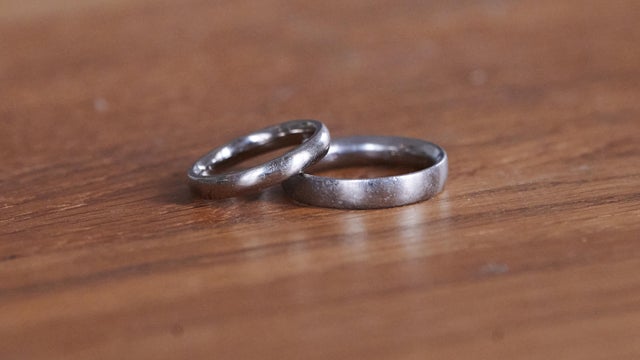 A pair of wedding rings lie on a wooden table.