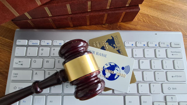 A gavel is placed on a computer keyboard next to several credit cards 