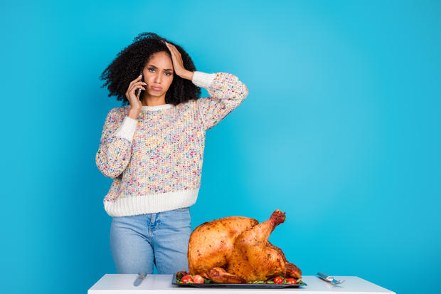 Photo portrait of attractive young woman unhappy confused talk phone celebrate thanksgiving dinner turkey isolated on blue color background 