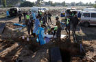 Members of civil defence remove bodies of people killed during hostilities between Israel and Hezbollah, including fighters, from a temporary cemetery to be taken for burial in their home town and villages, after a ceasefire between the two, in Tyre 