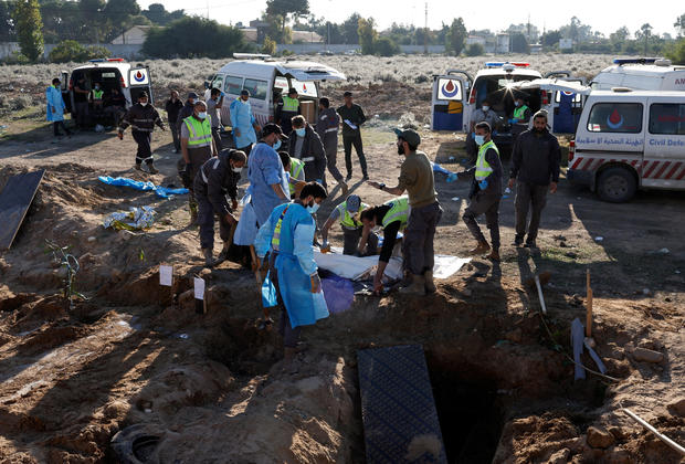 Members of civil defence remove bodies of people killed during hostilities between Israel and Hezbollah, including fighters, from a temporary cemetery to be taken for burial in their home town and villages, after a ceasefire between the two, in Tyre 