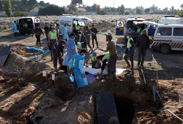 Members of civil defence remove bodies of people killed during hostilities between Israel and Hezbollah, including fighters, from a temporary cemetery to be taken for burial in their home town and villages, after a ceasefire between the two, in Tyre