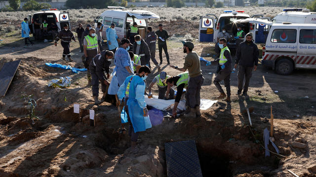 Members of civil defence remove bodies of people killed during hostilities between Israel and Hezbollah, including fighters, from a temporary cemetery to be taken for burial in their home town and villages, after a ceasefire between the two, in Tyre 