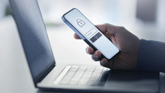 Man holding smart phone with data security on display at office 