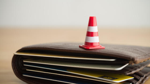 Close up red white traffic warning cones or pylon on leather wallet with many credit card. 