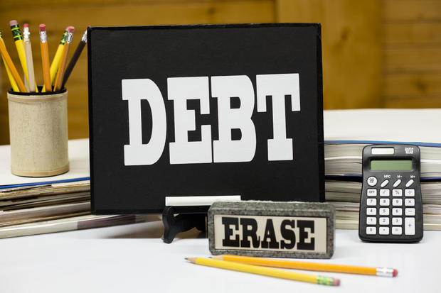 Word DEBT on chalkboard with eraser. 