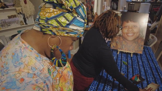 Two women look at photos laid out on a table 