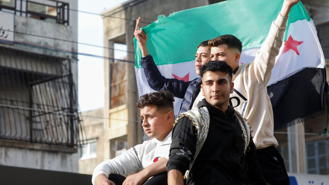 People hold the Syrian opposition flag as they celebrate in Jableh 