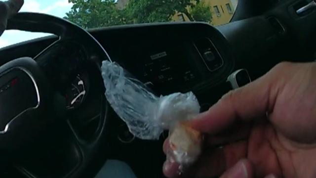 Police body camera footage shows a police lieutenant holding a clear baggie containing a white substance while sitting in the driver's seat of a vehicle. 