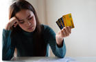 Stressed asian woman holding credit card and expenses bills paper. Woman having problem income. Unhappy woman without money to pay credit card. 