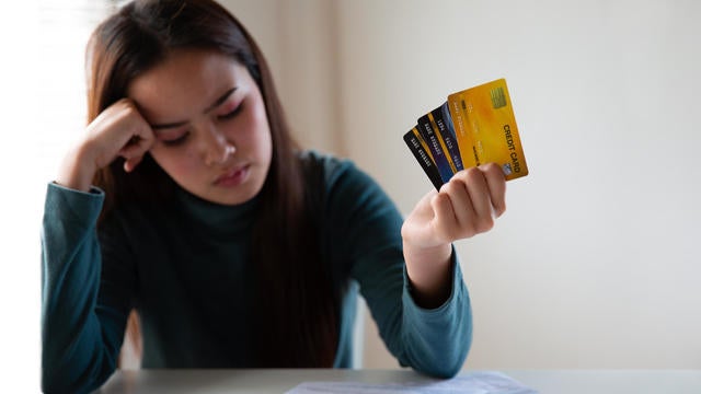 Stressed asian woman holding credit card and expenses bills paper. Woman having problem income. Unhappy woman without money to pay credit card. 