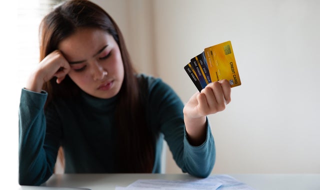 Stressed asian woman holding credit card and expenses bills paper. Woman having problem income. Unhappy woman without money to pay credit card. 
