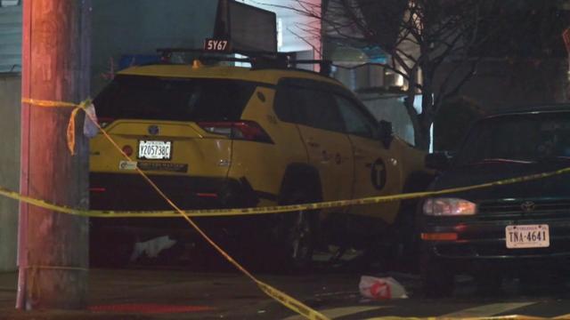 A yellow taxi cab sits on a sidewalk behind police tape. 